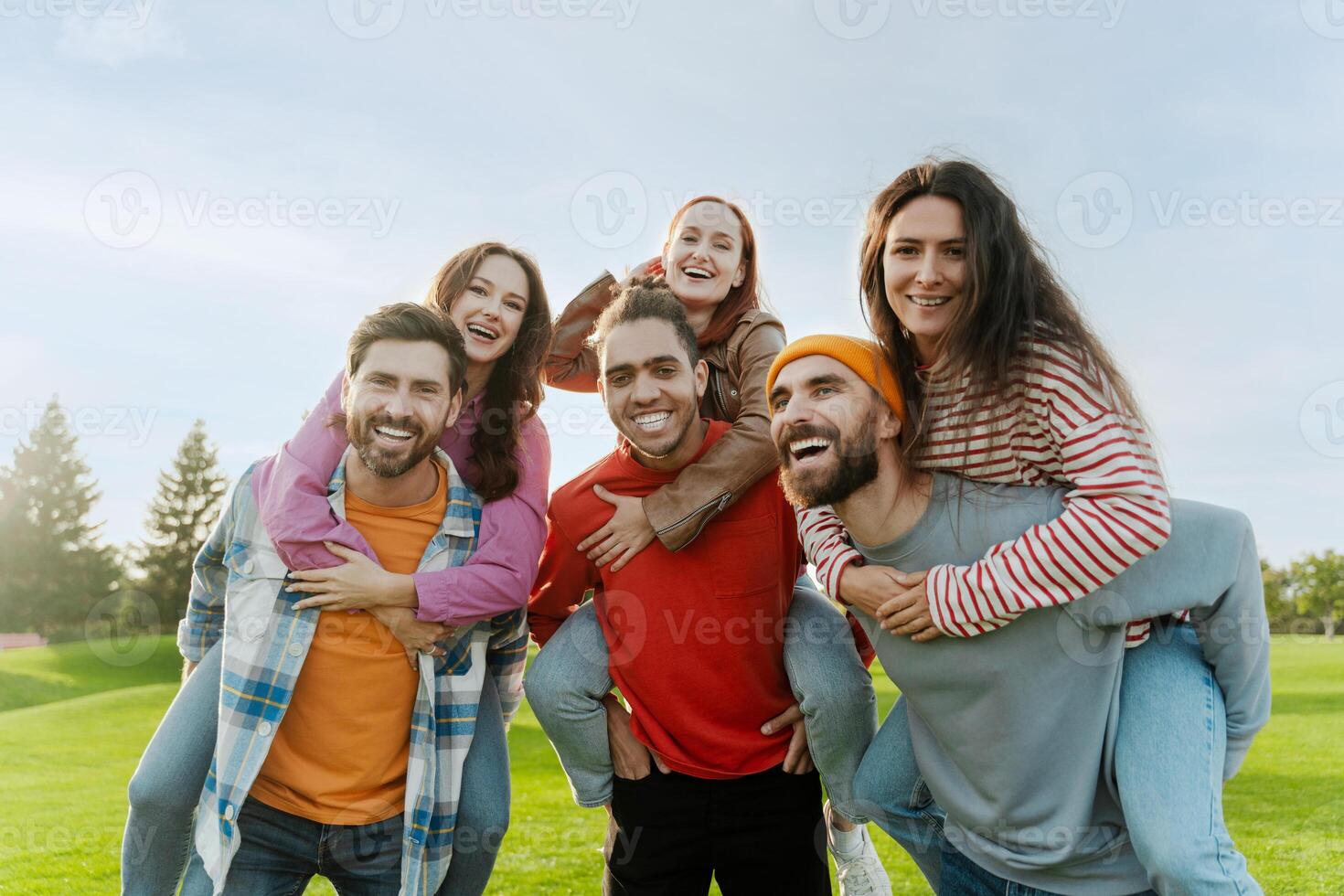 Group of friends having fun piggybacking in park photo