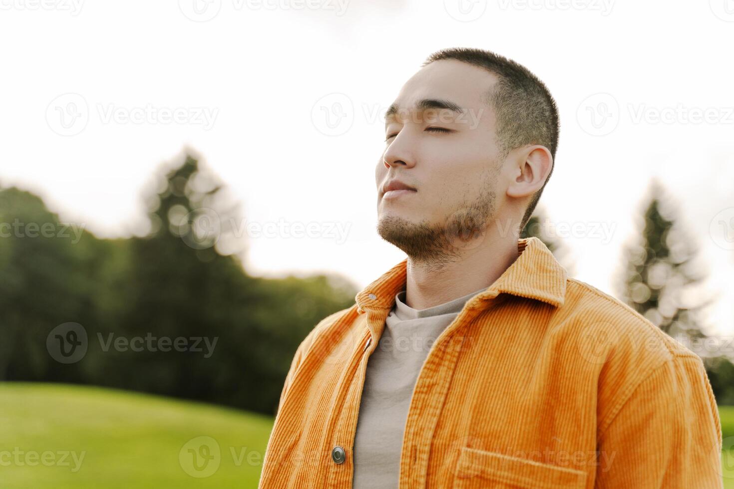 Young man breathing fresh air in nature taking a deep breath photo