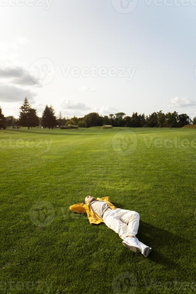 Young man relaxing lying down on a green meadow photo