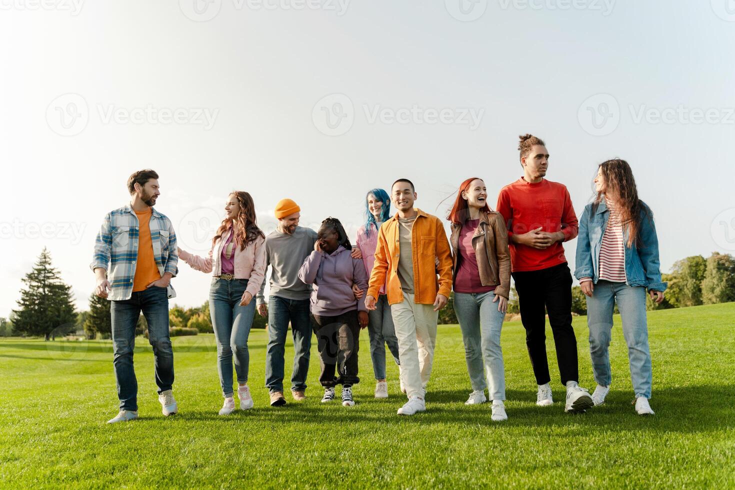 Group of diverse friends walking and talking together in park photo