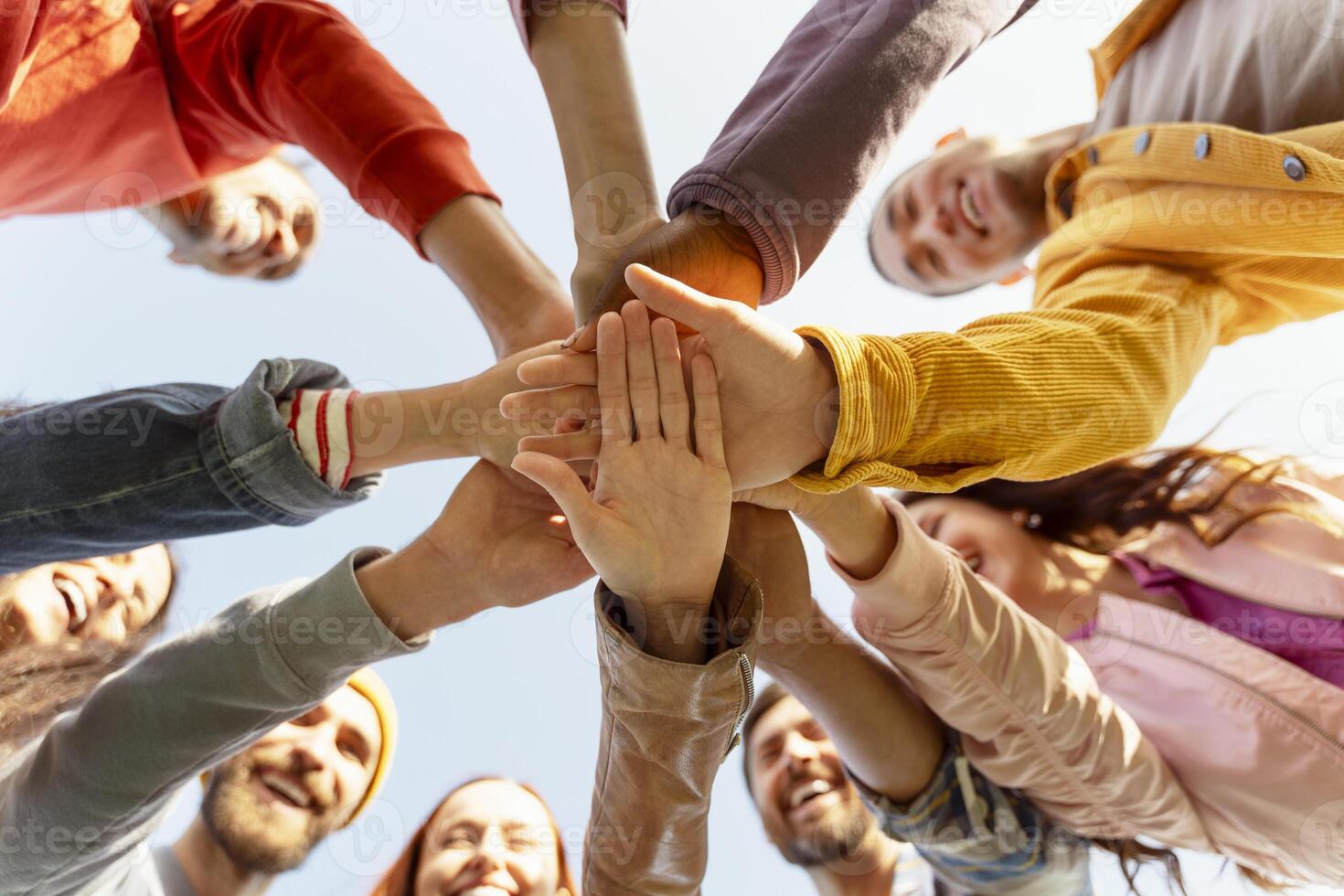 Group of people joining hands in a huddle smiling and bonding photo