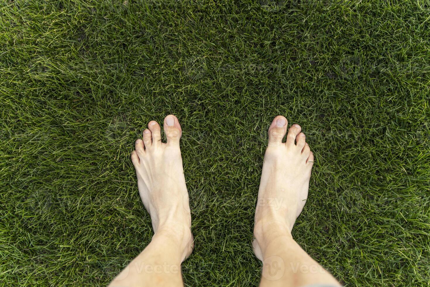 Man standing barefoot on green grass lawn texture background photo