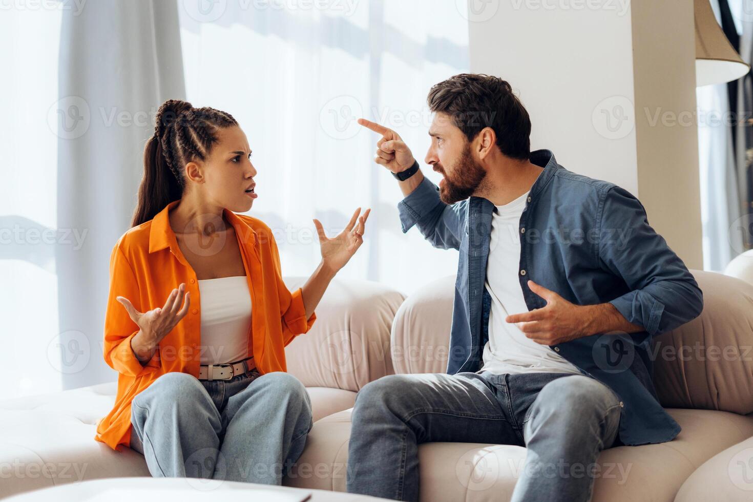 Portrait of angry unhappy couple quarreling sitting on sofa at home, gesturing. Relationship concept photo