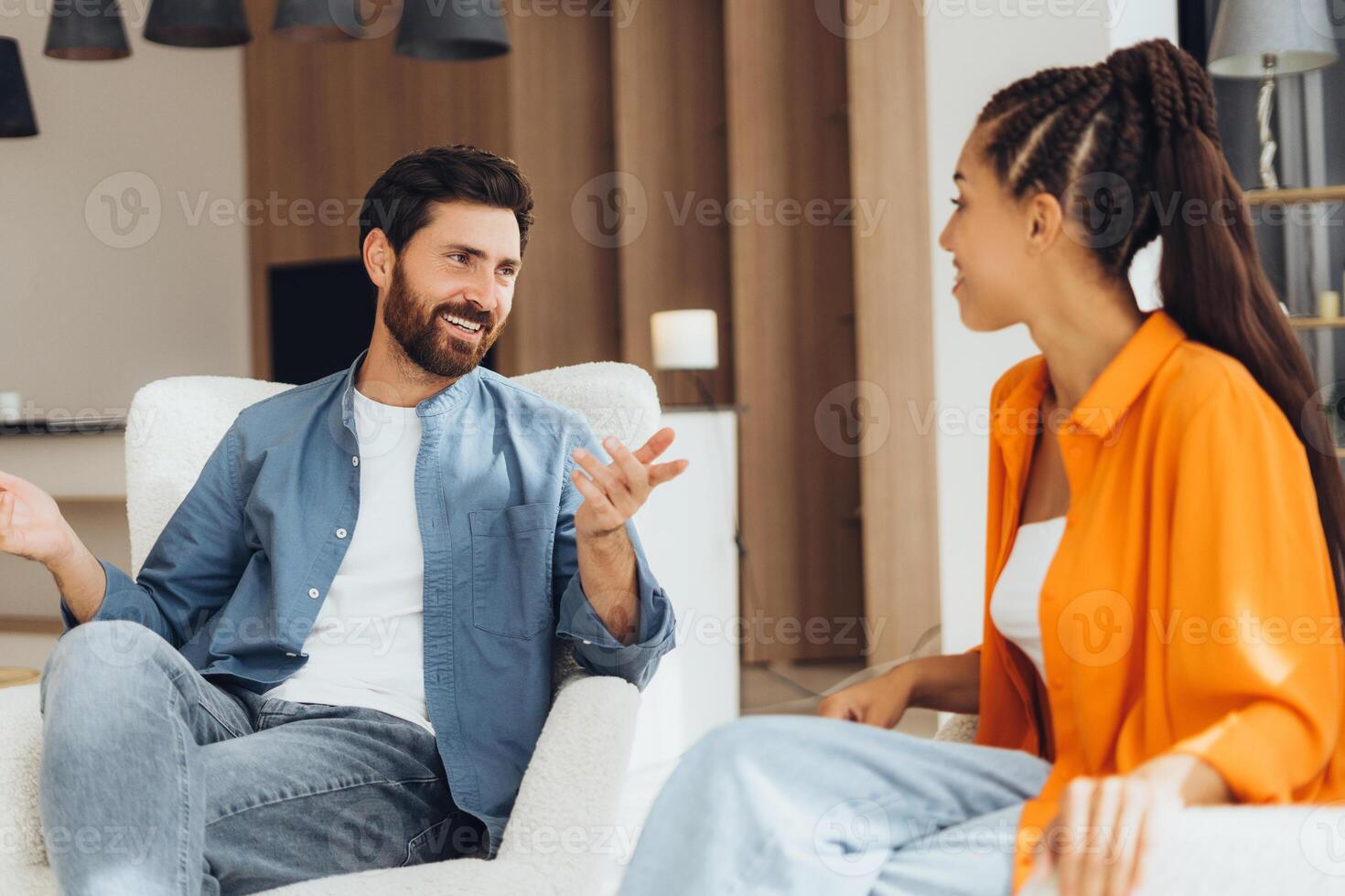 Happy, middle aged man and woman talking, sitting together in comfortable chair gesturing photo