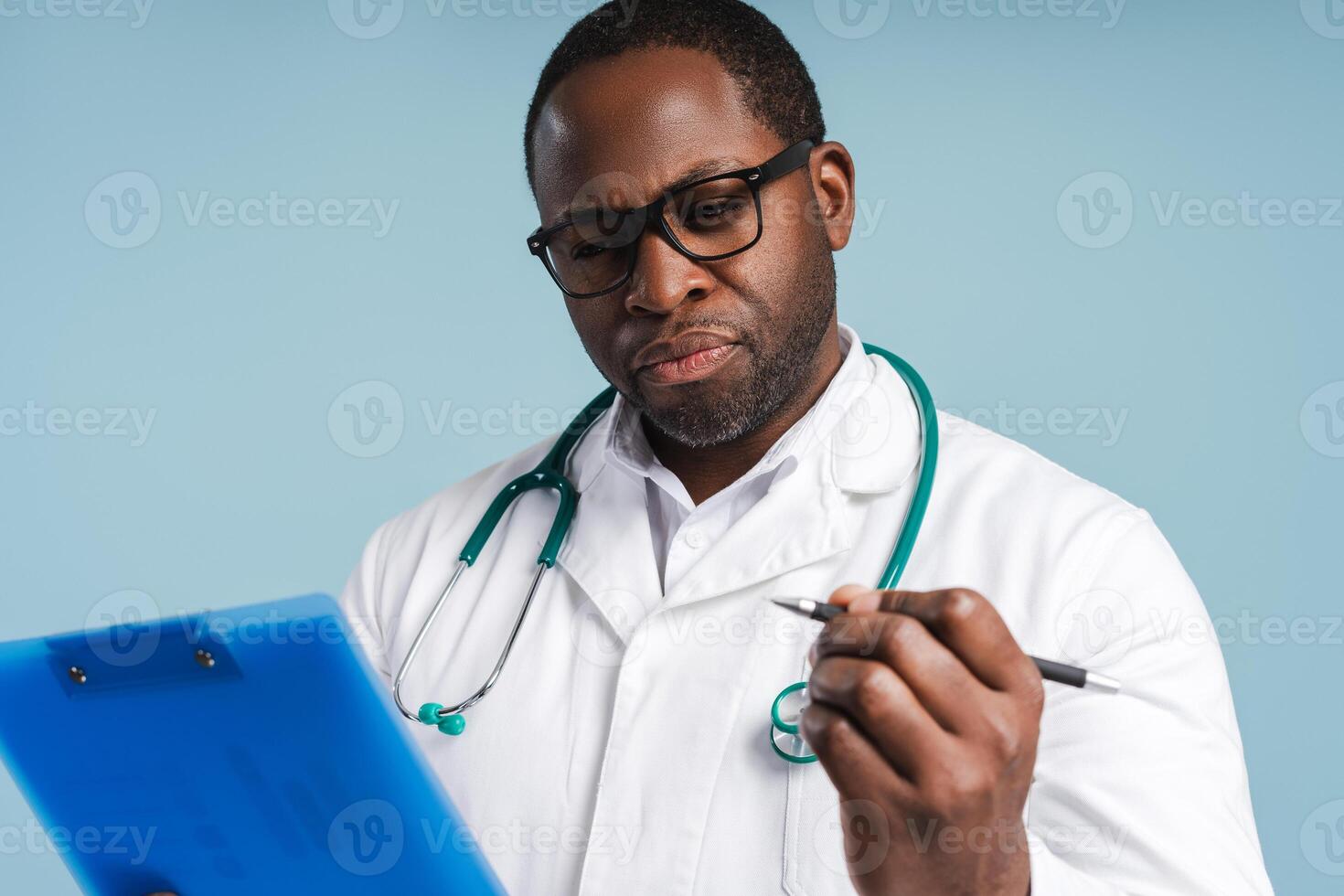 African American doctor making notes posing in studio, isolated on blue photo