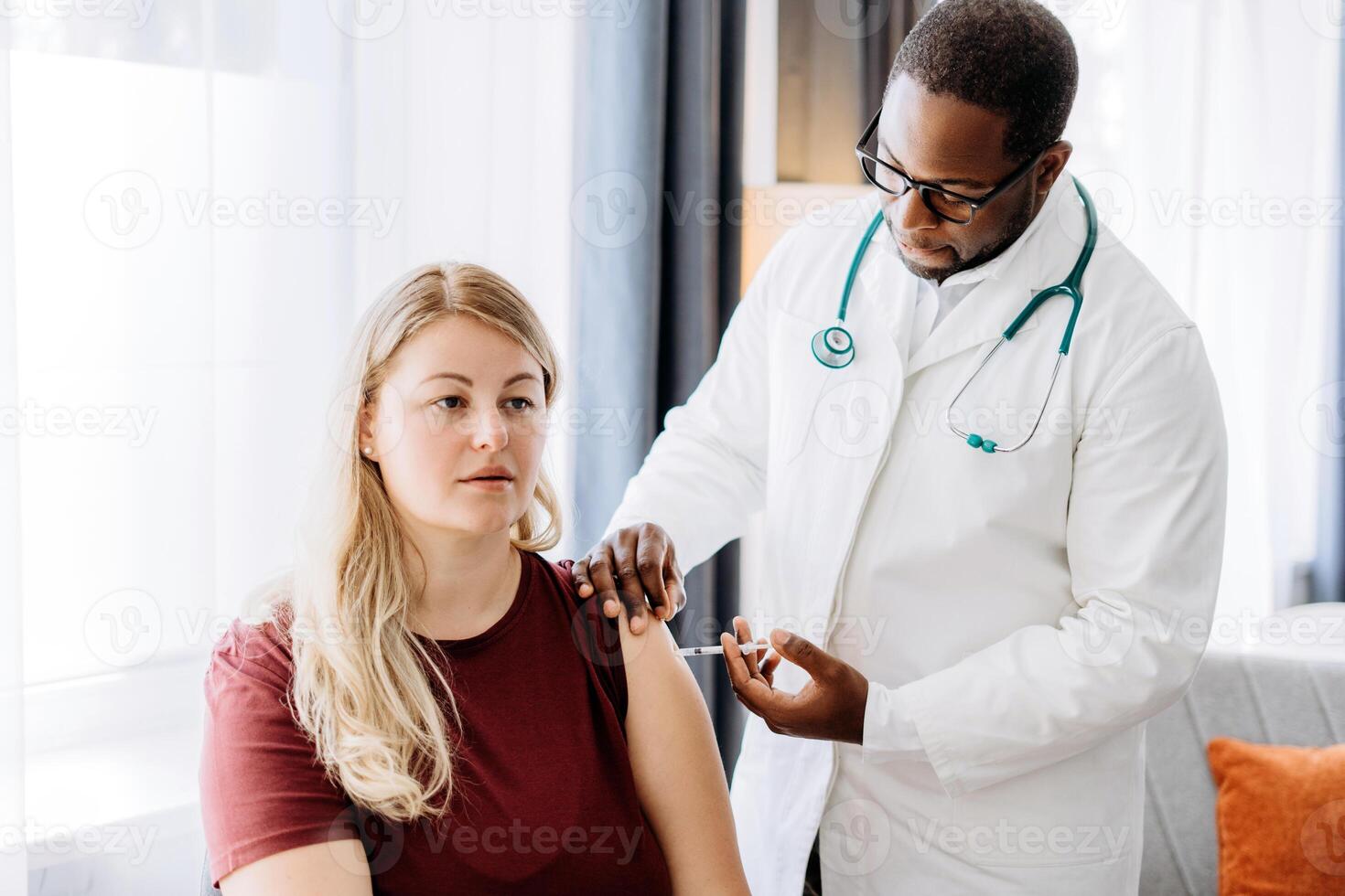 African American doctor in the hospital making an injection in the female patient arm vaccination photo
