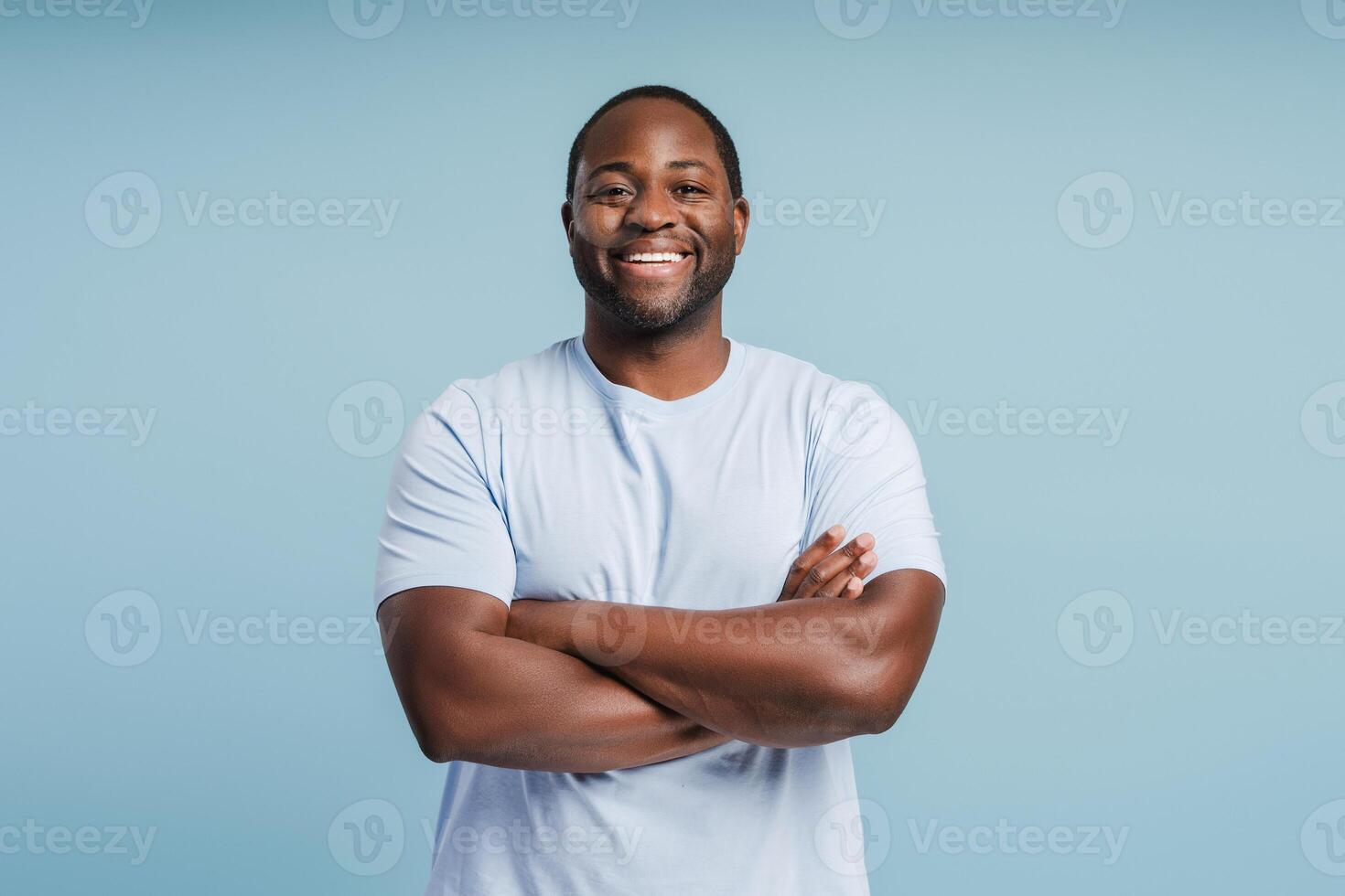 Happy young African American man posing with arms crossed in studio photo