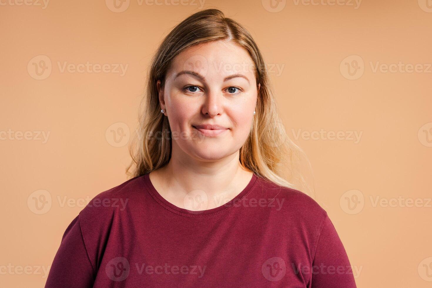 Pretty plus size Caucasian woman posing looking at camera, isolated on beige photo