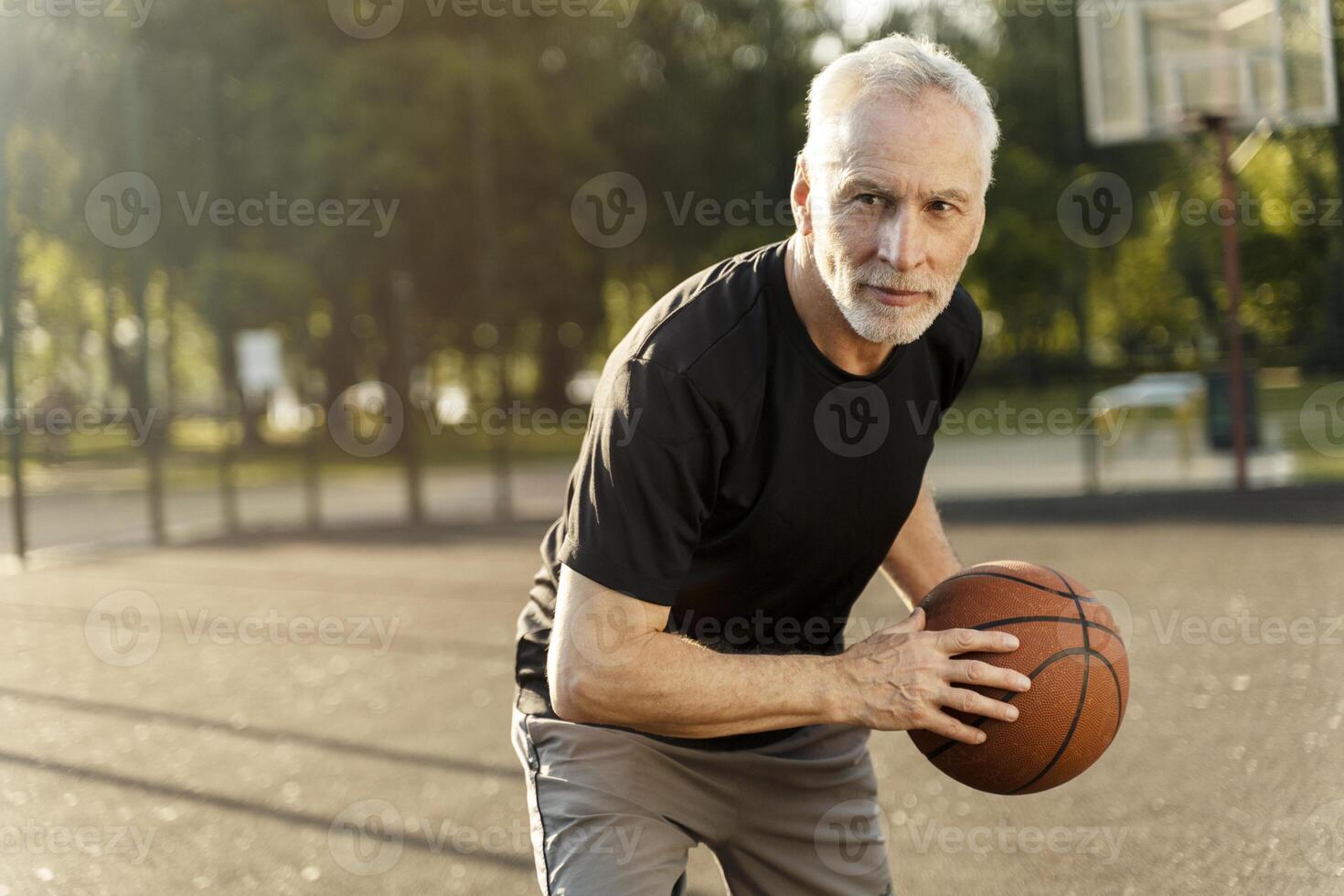 Senior man playing basketball on outdoor court, embracing active lifestyle photo