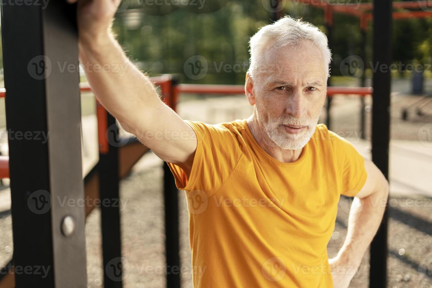 Senior man stretching at outdoor gym, embracing fitness and vitality in retirement photo