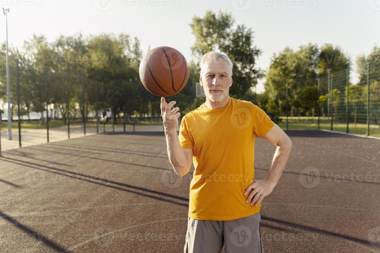 Senior man spinning basketball on finger at outdoor court photo