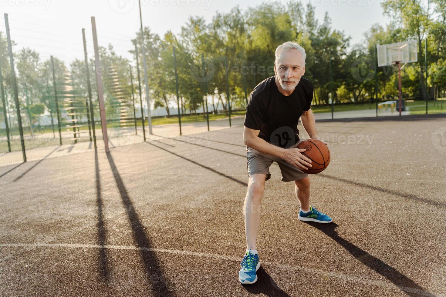 Senior man playing basketball on outdoor court, active retirement lifestyle photo
