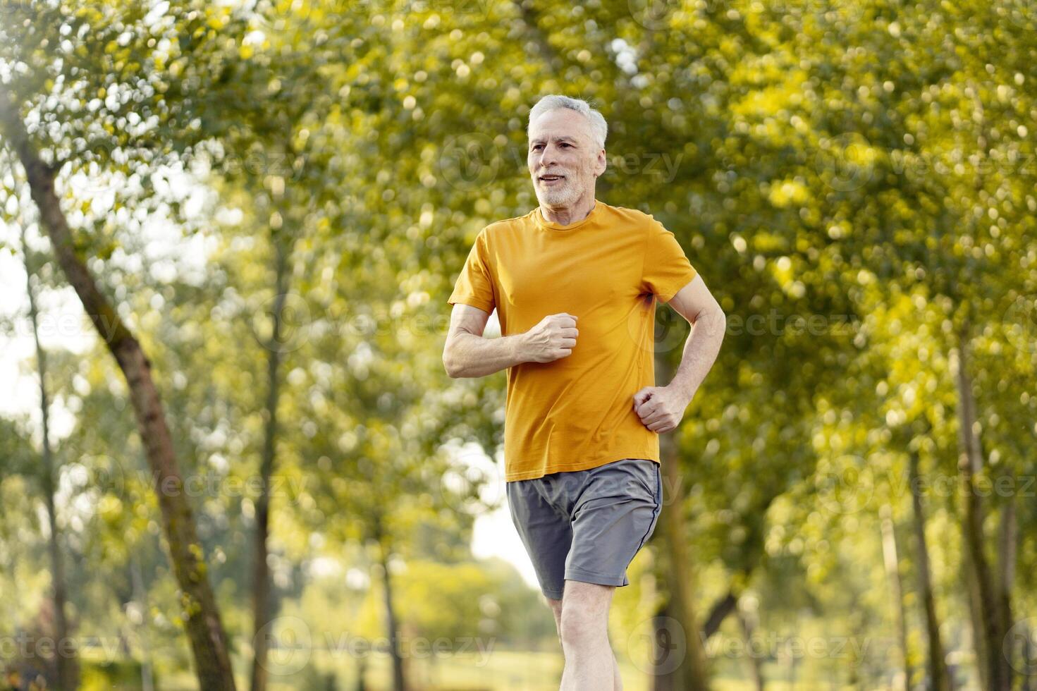 Senior man enjoying running in the park during summertime photo