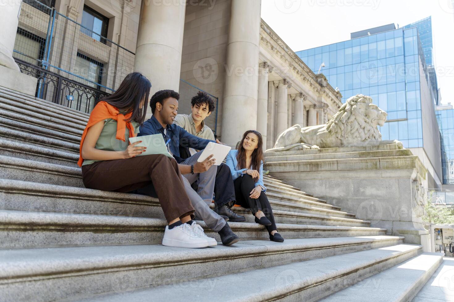 Students collaborating on university campus steps using digital tablet photo