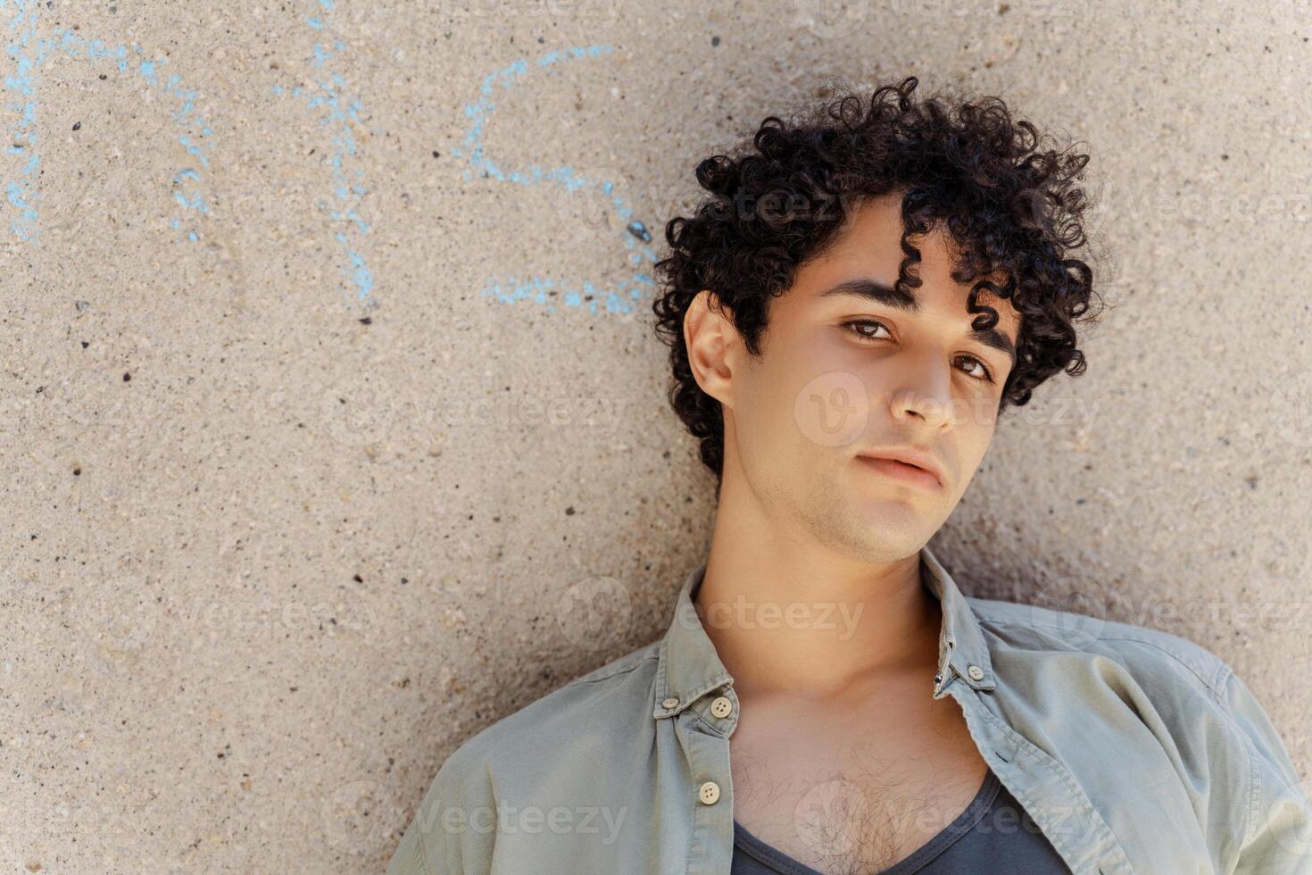Young man leaning against concrete wall looking serious photo