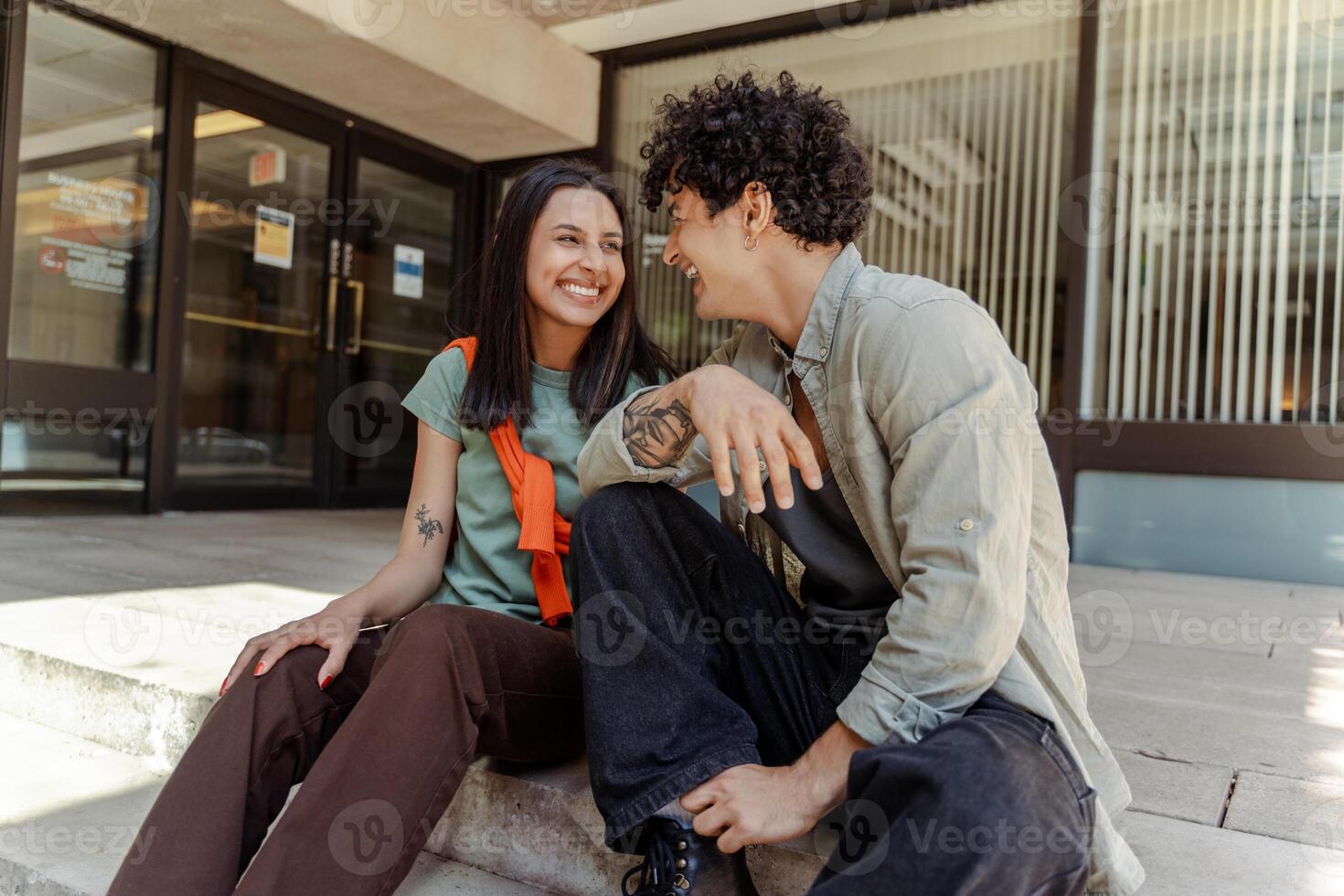 Young couple sharing a laugh while sitting on steps outside photo