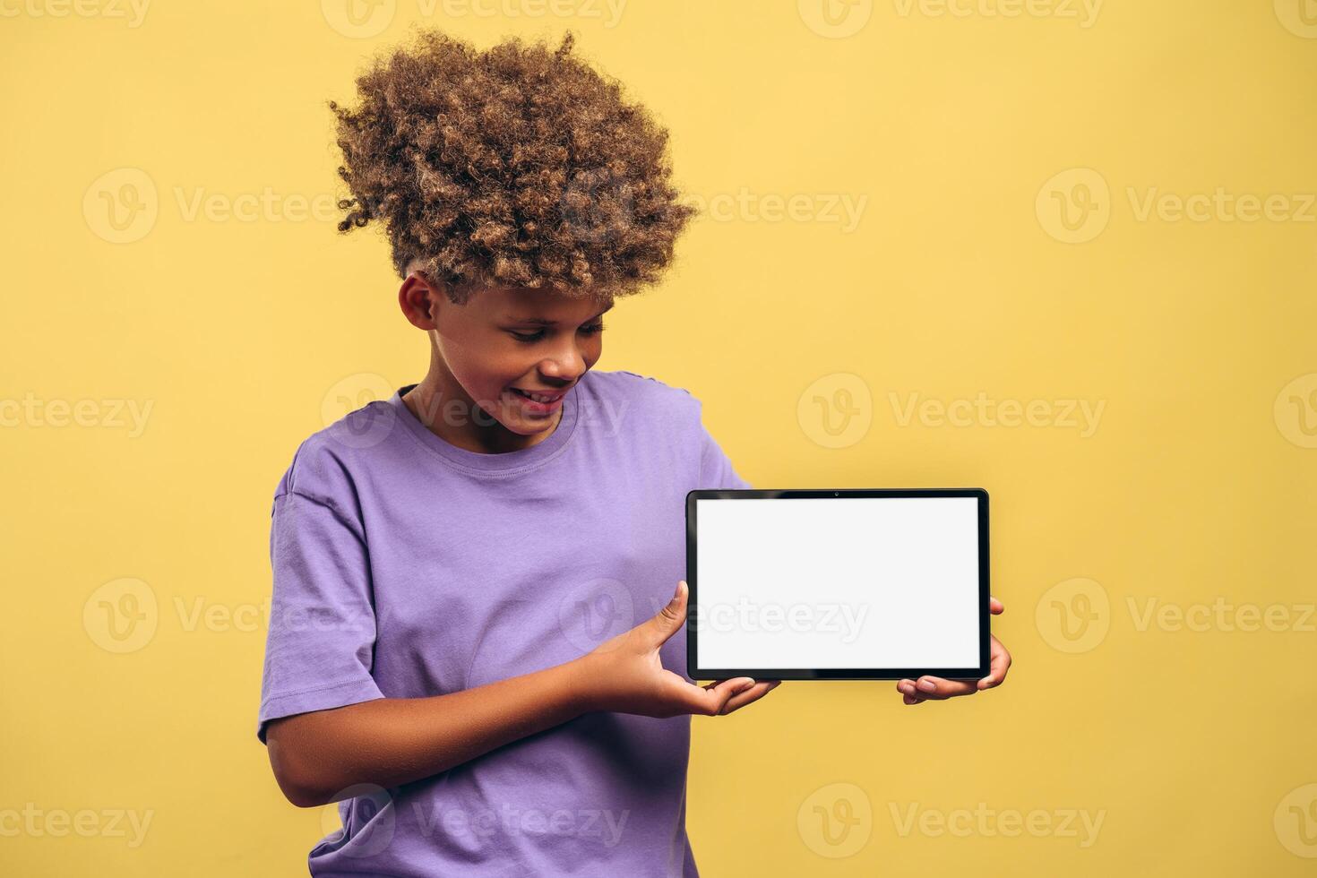 Smiling African American boy holding digital tablet with empty, white screen mockup photo