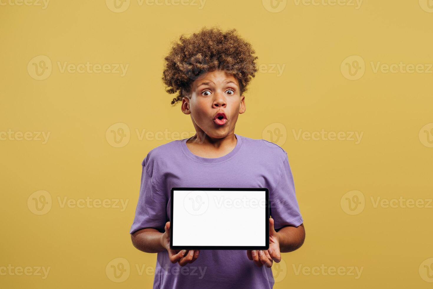 Portrait of excited African American boy holding digital tablet with empty, white screen mockup photo