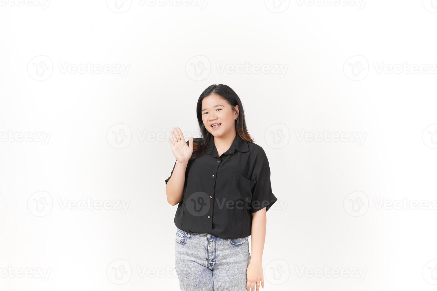 beautiful Asian woman smiles warmly while making a friendly 'hi' hand gesture against a white background photo
