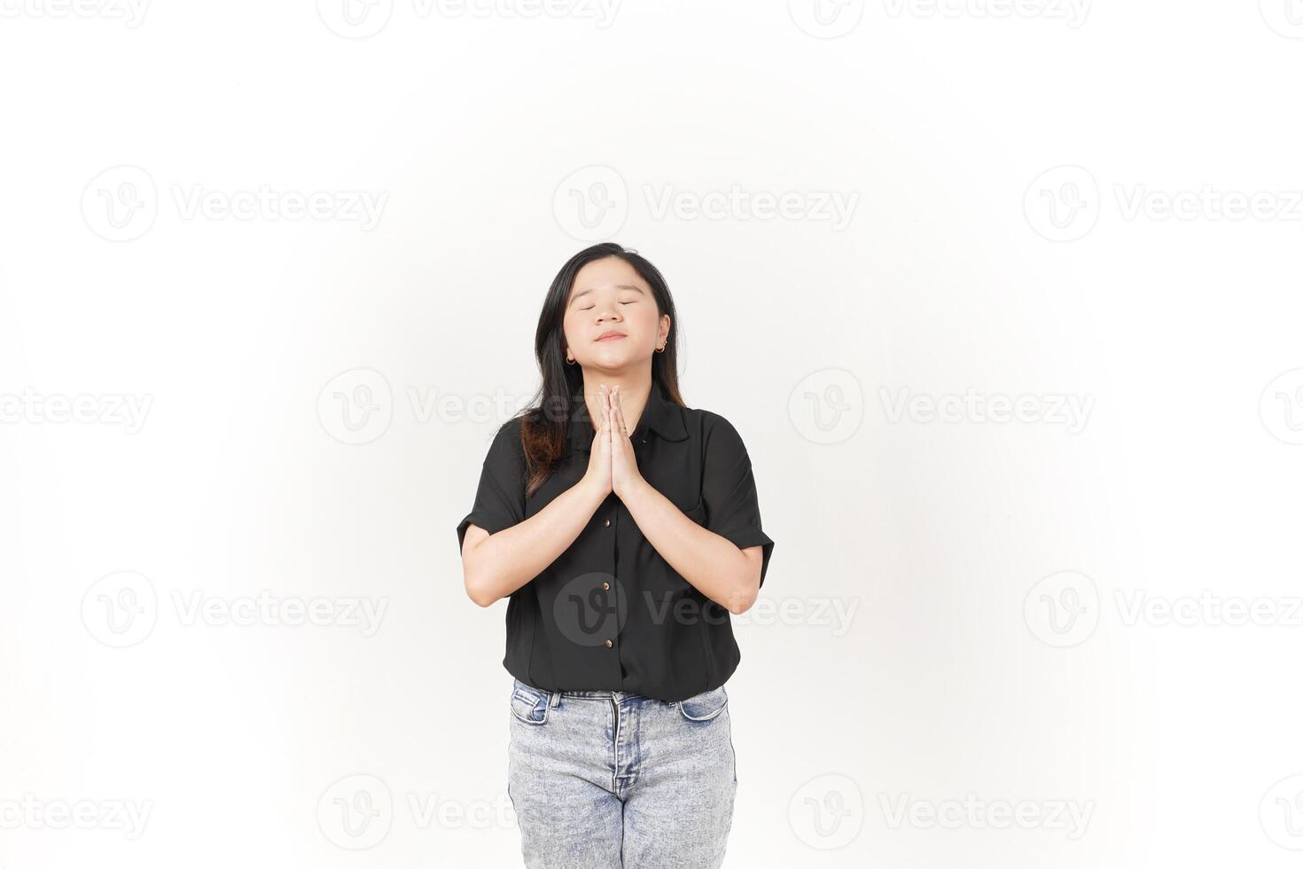 beautiful Asian woman in a praying pose, hands together and eyes closed, expressing hope against a white background photo