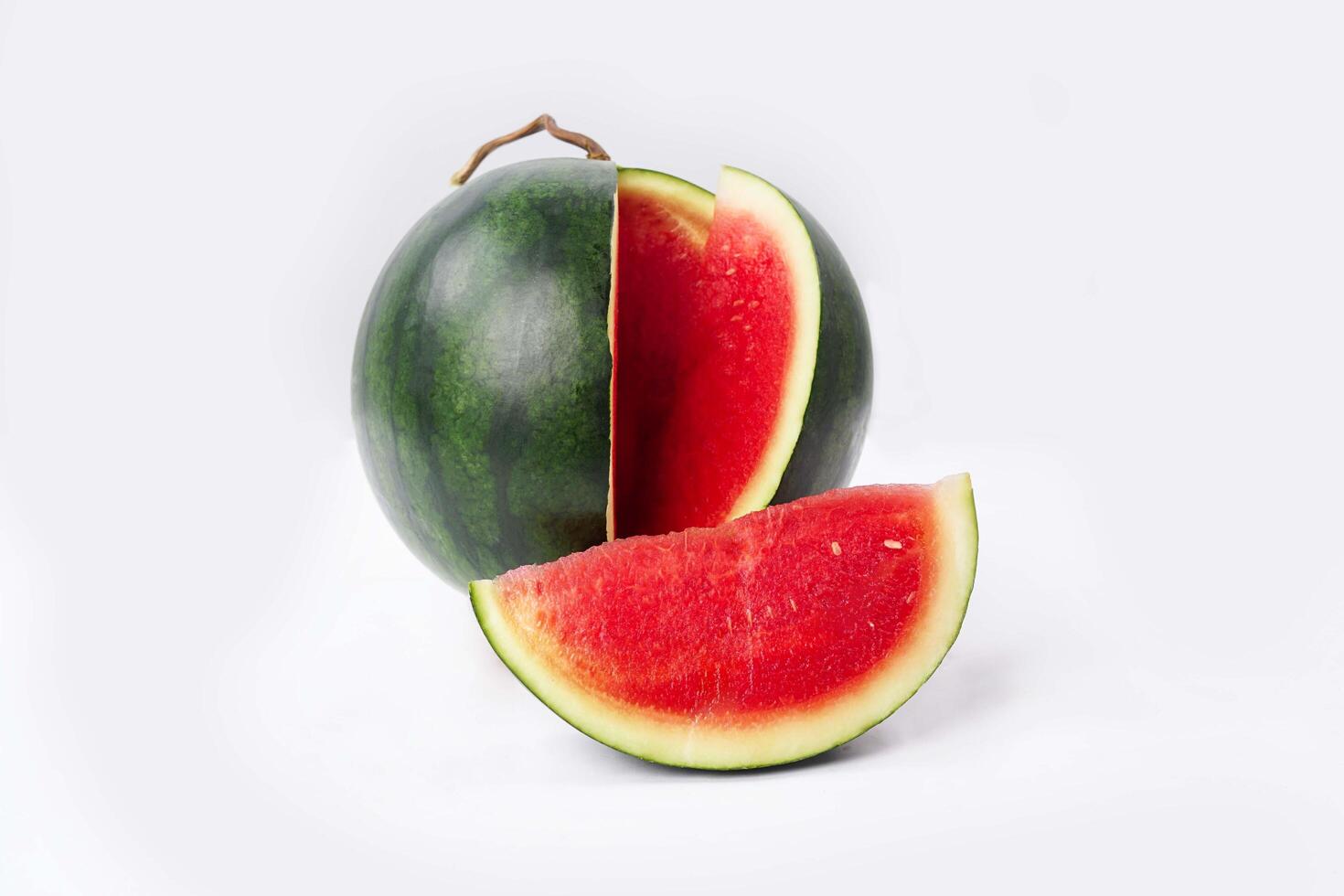 Whole watermelon and seeded slices seen front and top on a white background. Watermelon slices are red, seedy and juicy. photo