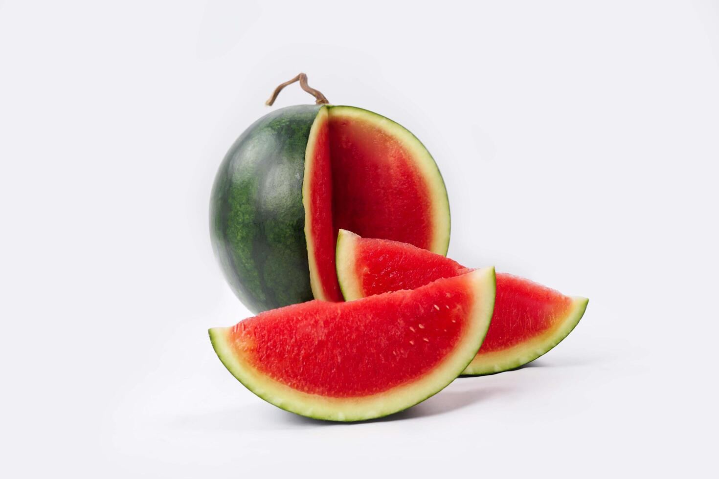 Whole watermelon and seeded slices seen front and top on a white background. Watermelon slices are red, seedy and juicy. photo