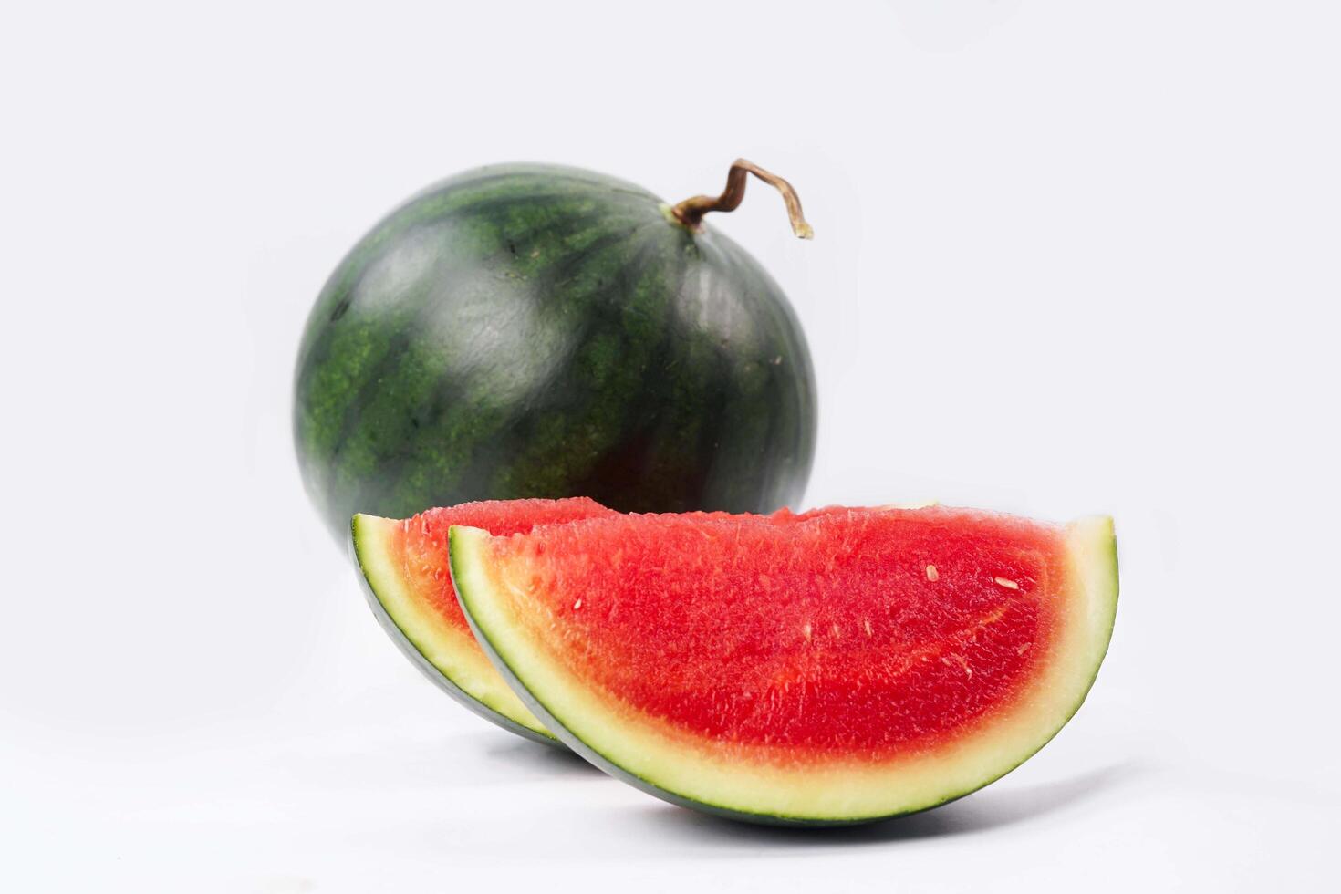 Whole watermelon and seeded slices seen front and top on a white background. Watermelon slices are red, seedy and juicy. photo