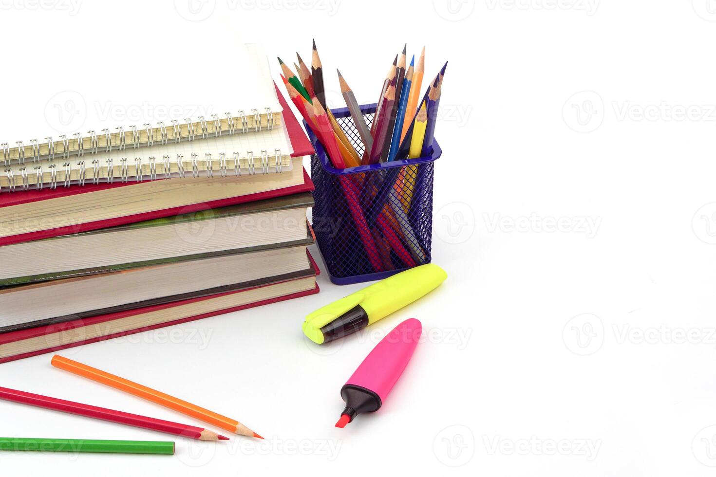 Crayon or colored pencils in box with side stack of books and school supplies on with background. Learning, study and office equipment concept. photo