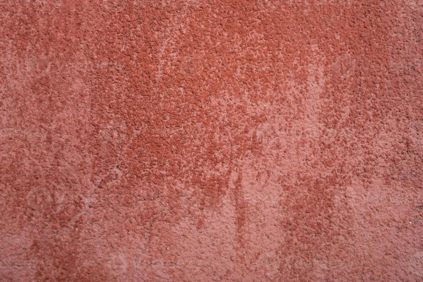 Vibrant textured wall with a warm reddish hue illuminated by soft light in an urban setting photo