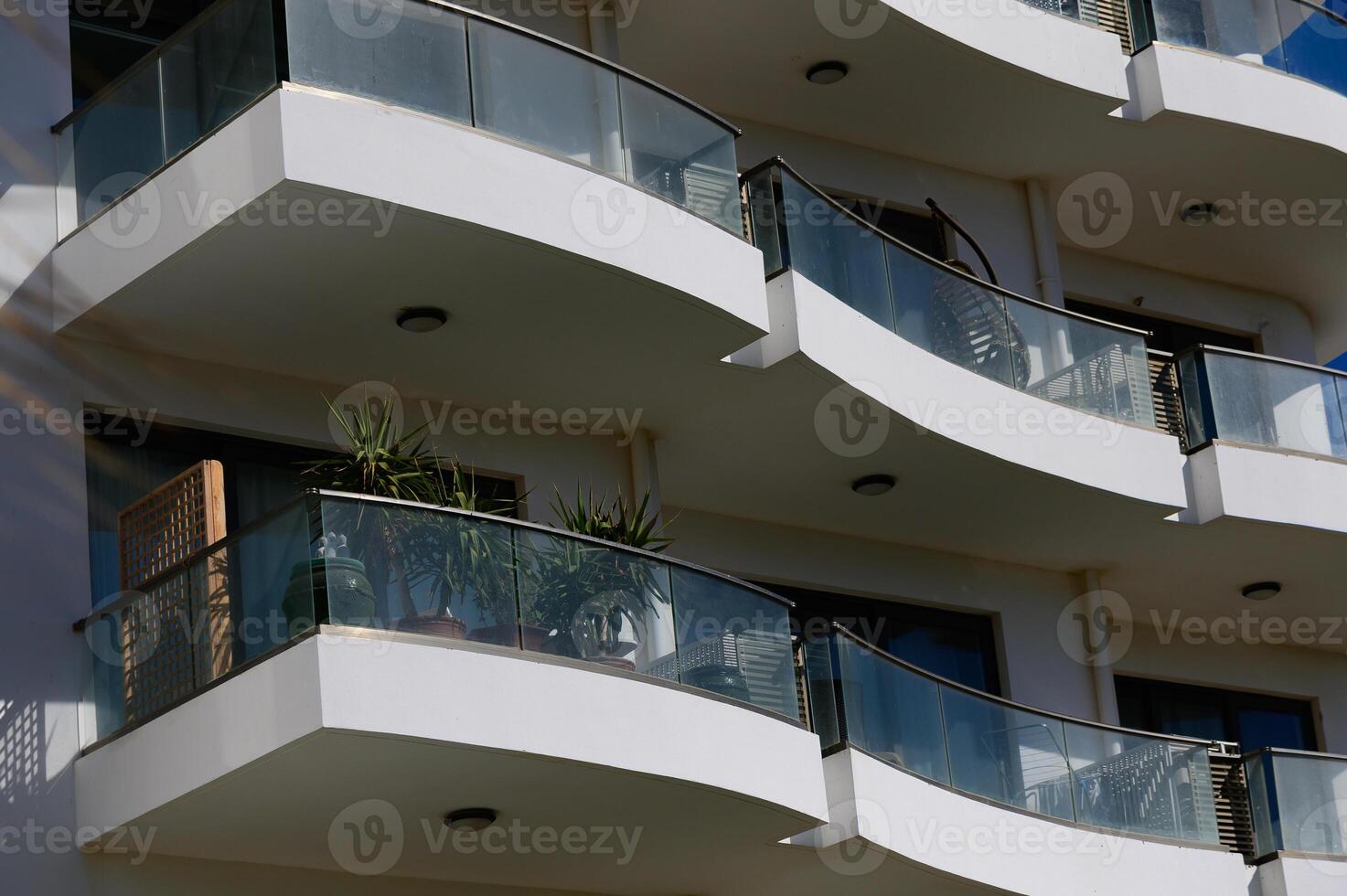 Elegant modern balconies adorned with greenery under a bright sky at a stylish urban building photo