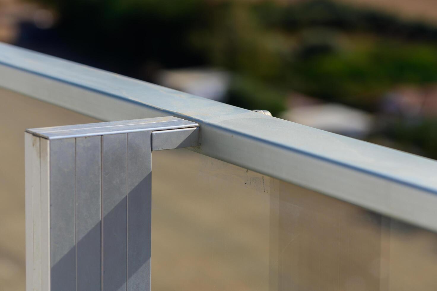 A Bright Sunny Day Reveals Modern Architectural Details of a Balcony Railing Overlooking a Serene Landscape Filled With Greenery photo