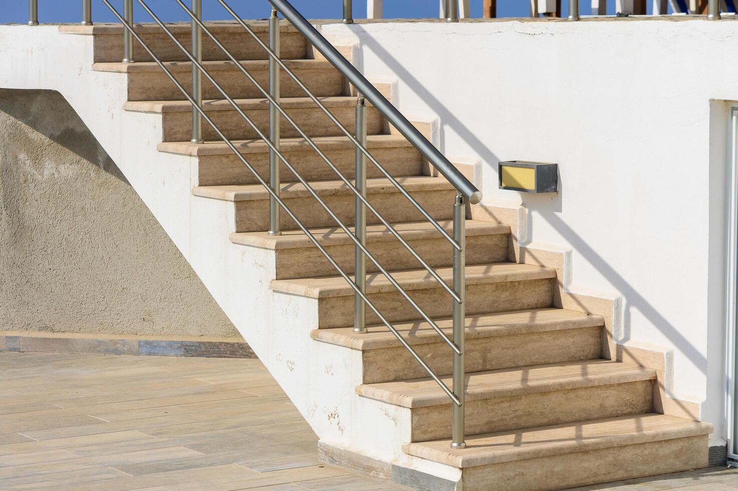 Staircase Leading to a Sunlit Terrace, Inviting Relaxation and Enjoyment by the Sea in a Bright Coastal Setting photo