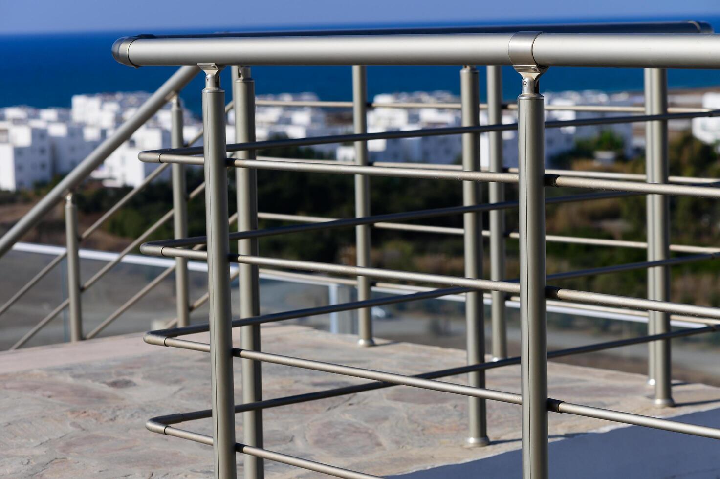 Modern Metal Railing Overlooking a Serene Coastal View Under a Clear Blue Sky in a Tranquil Location photo