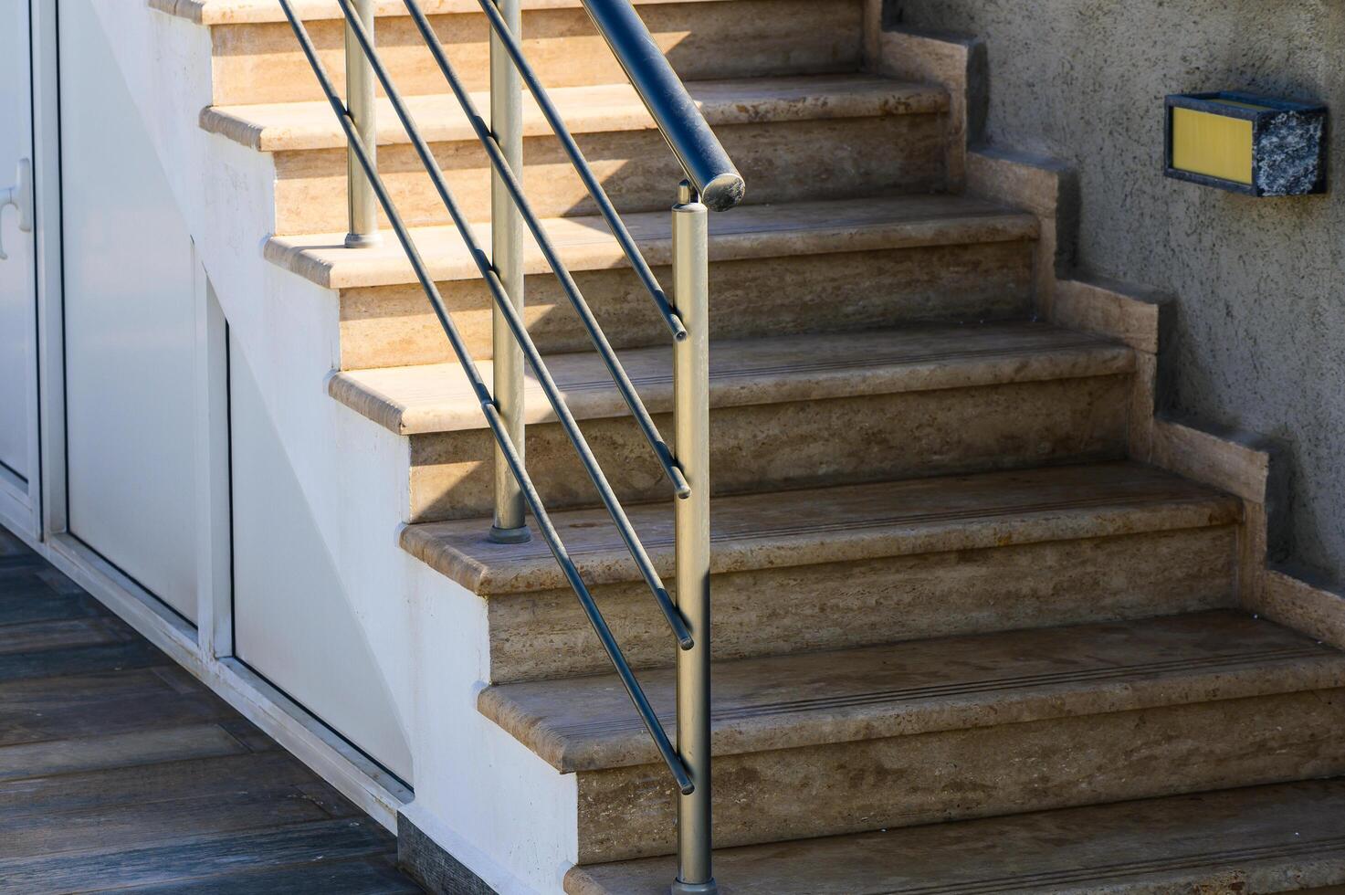 Modern Staircase With Polished Stone Steps and Sleek Railing in Natural Daylight at a Contemporary Home Entrance photo