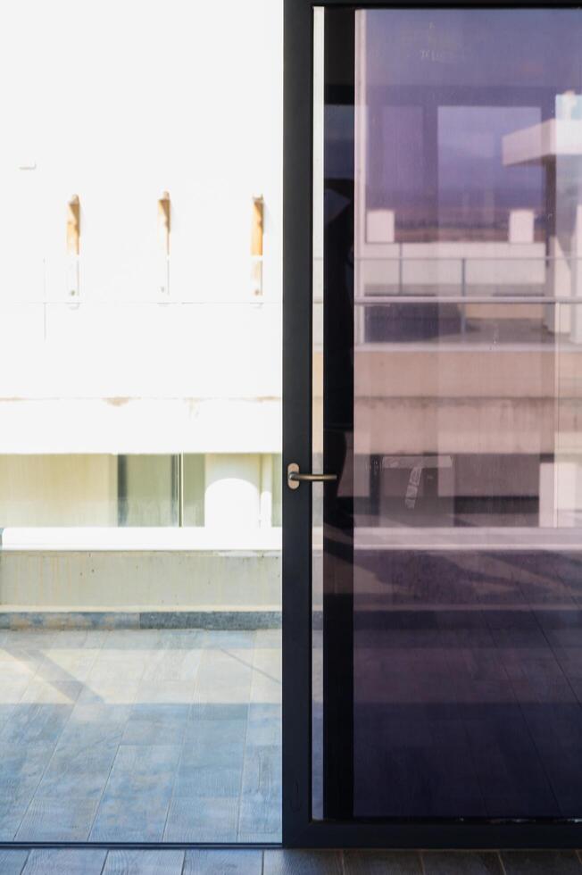 A Sleek Modern Door Opens to Reveal a Bright, Sunlit Balcony With Architectural Simplicity During a Serene Afternoon photo