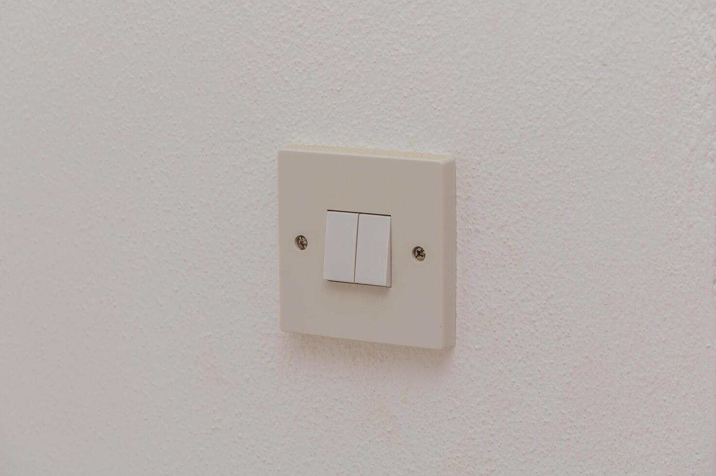 A Simple Light Switch on a White Wall Providing Illumination in a Minimalist Room Setting During Daytime Hours photo