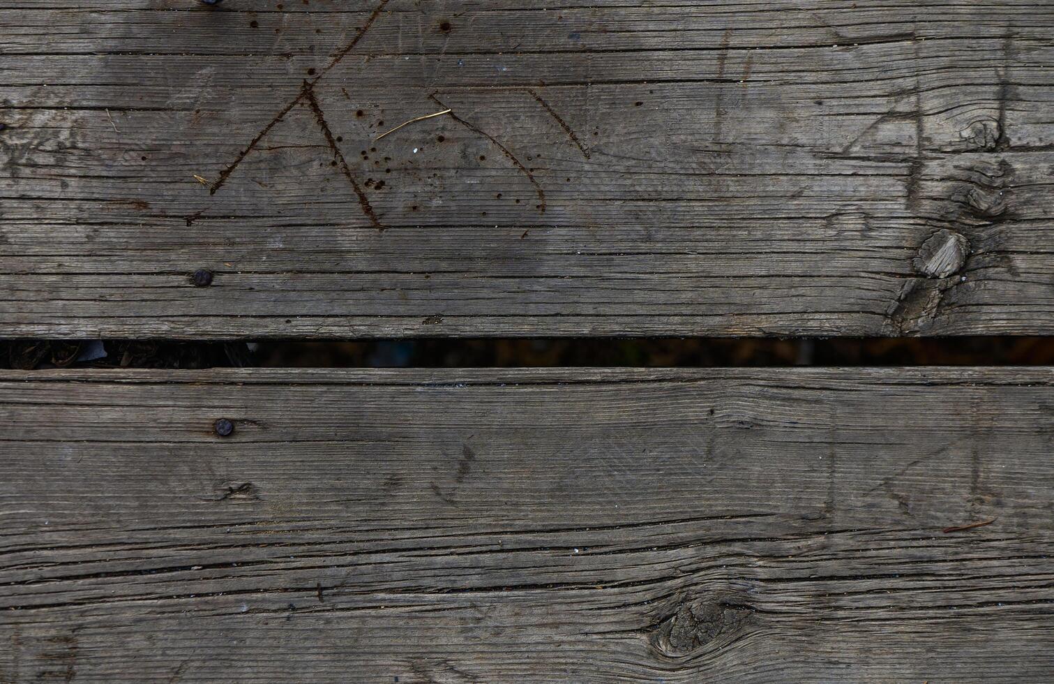Weathered wooden planks with gaps showing signs of age and wear in a rustic setting photo