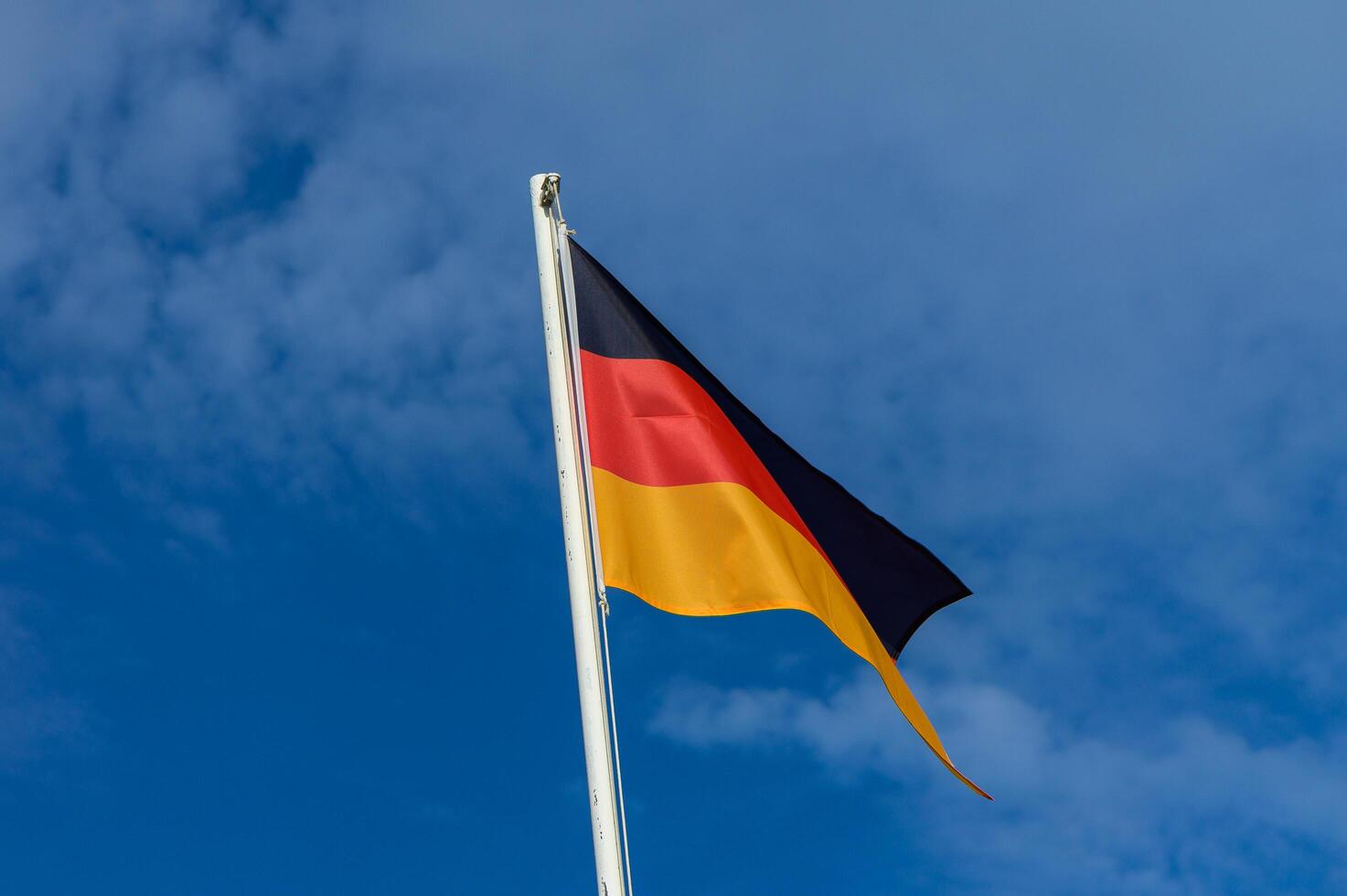 German flag waving proudly against a clear blue sky during a sunny day, symbolizing national pride and unity in Germany photo