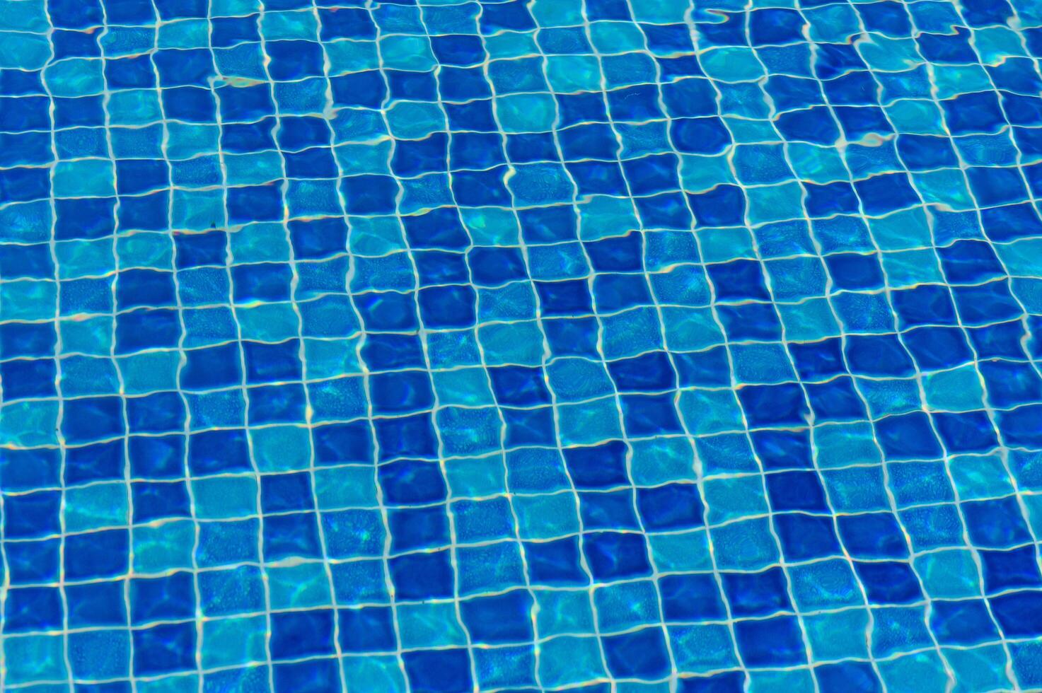 A Captivating View of Shimmering Blue Tiles Reflecting Sunlight in a Tranquil Swimming Pool on a Sunny Day photo