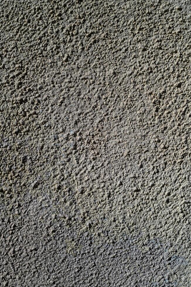 Textured surface of rough concrete wall in natural light creating an abstract design at midday photo