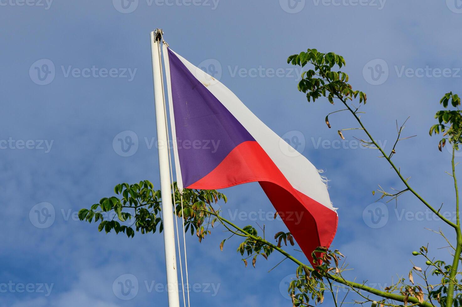 Waving flag of the Czech Republic against a blue sky, symbolizing national pride and heritage in a serene landscape photo