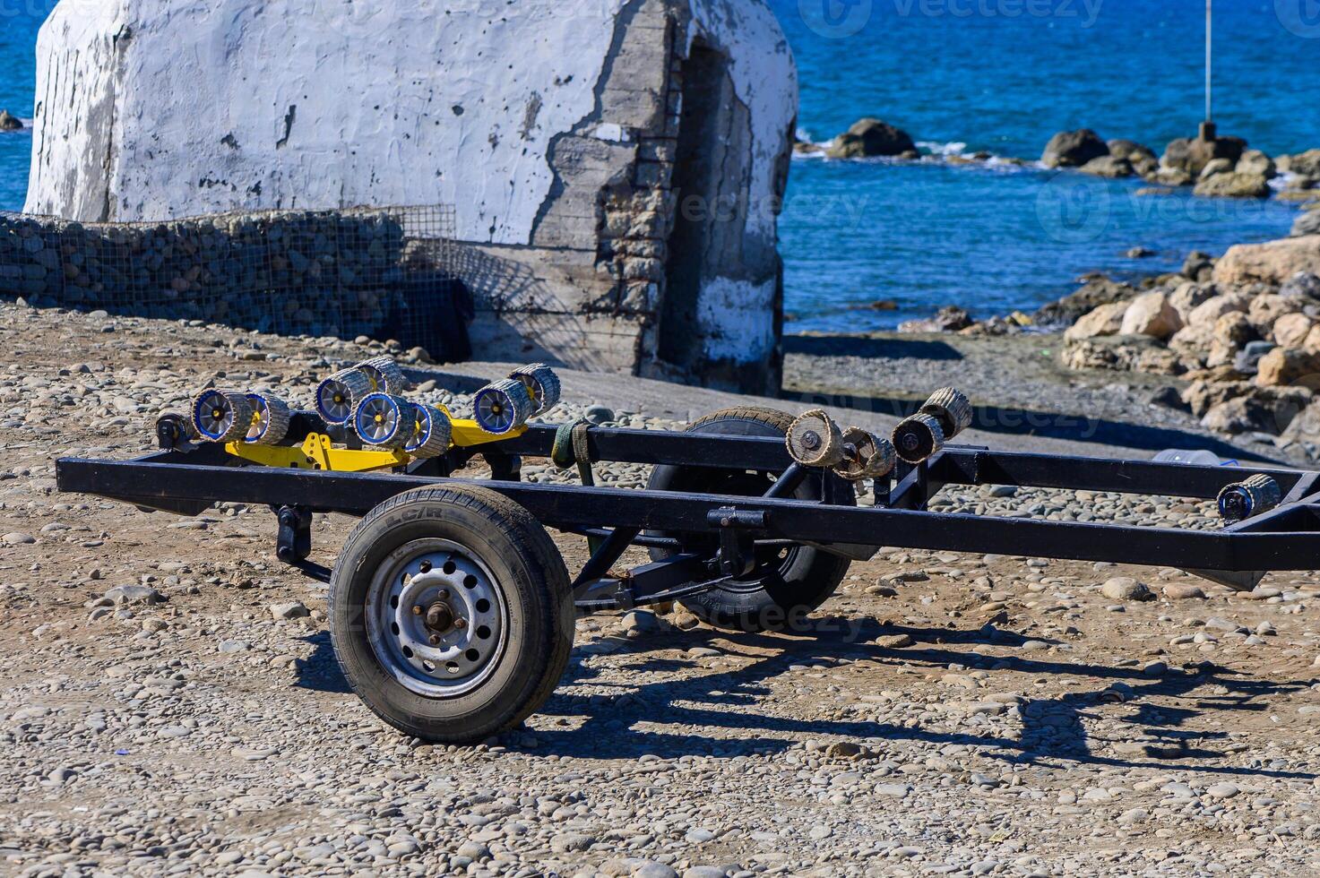A rugged trailer ready for adventure by the serene coastal waters at midday photo