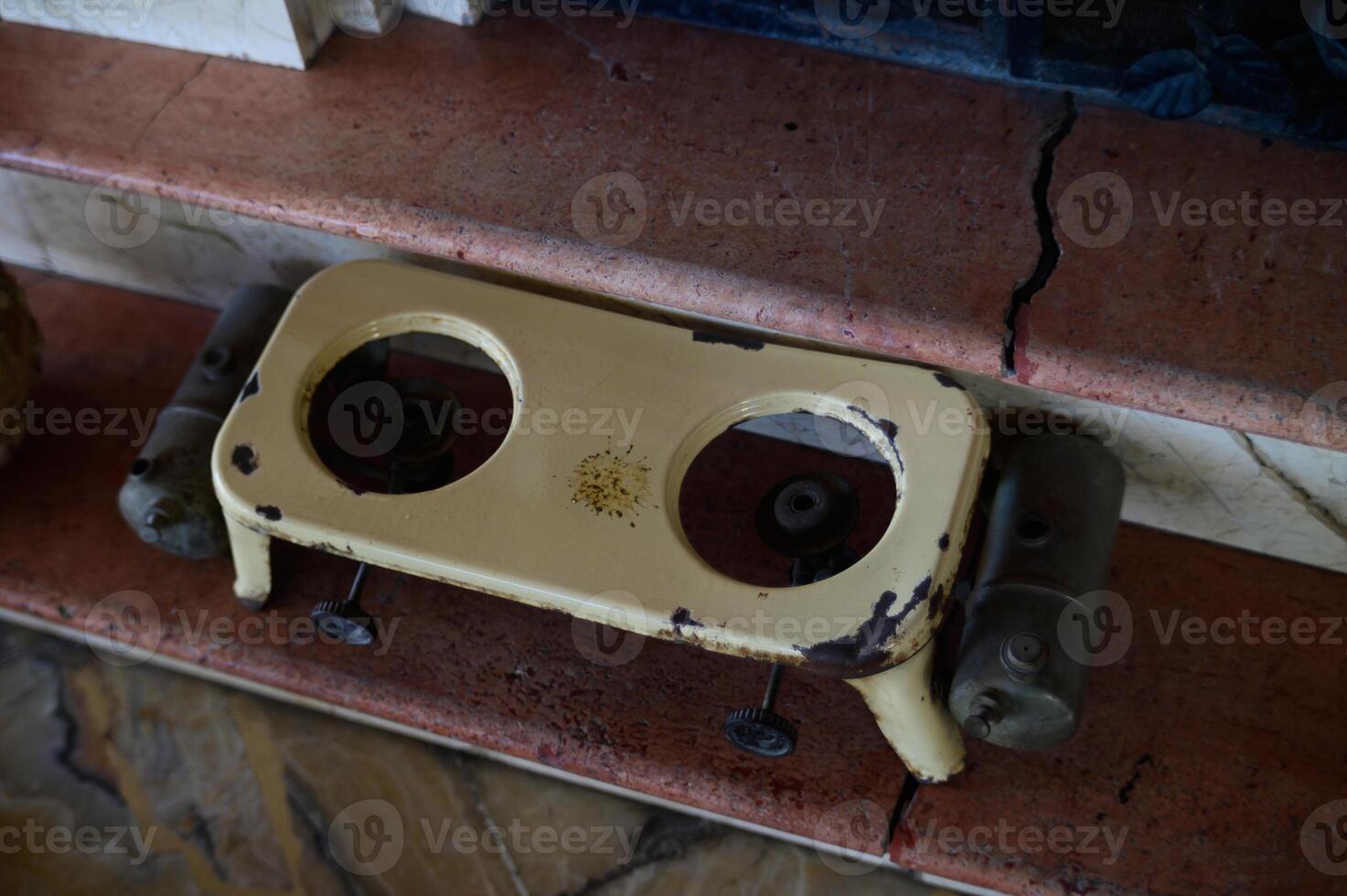 Rusty vintage toy car chassis rests on a worn stone pedestal in a forgotten corner of a sunlit room photo