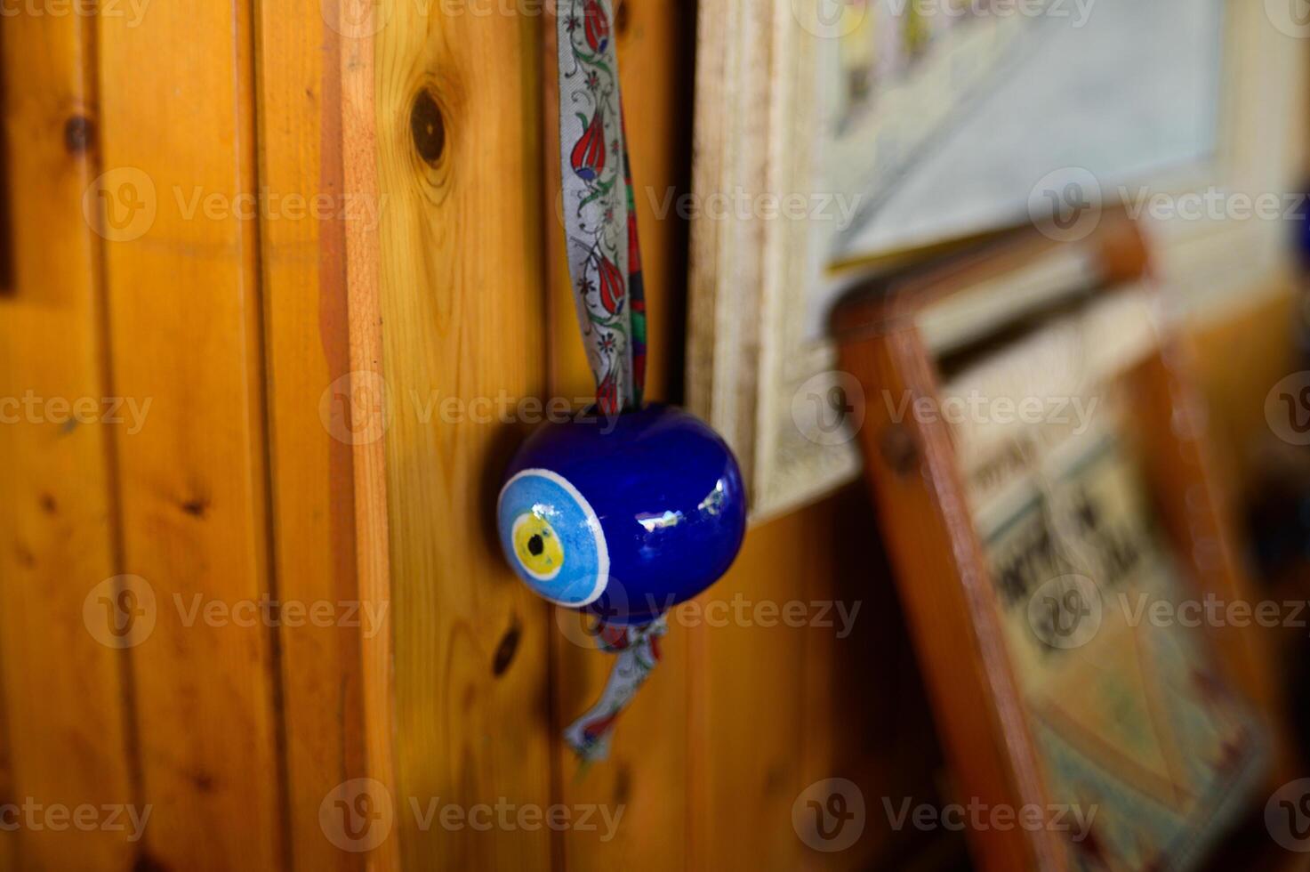 A handcrafted blue bell with intricate details hanging on a warm wooden wall in a cozy rustic cabin setting photo