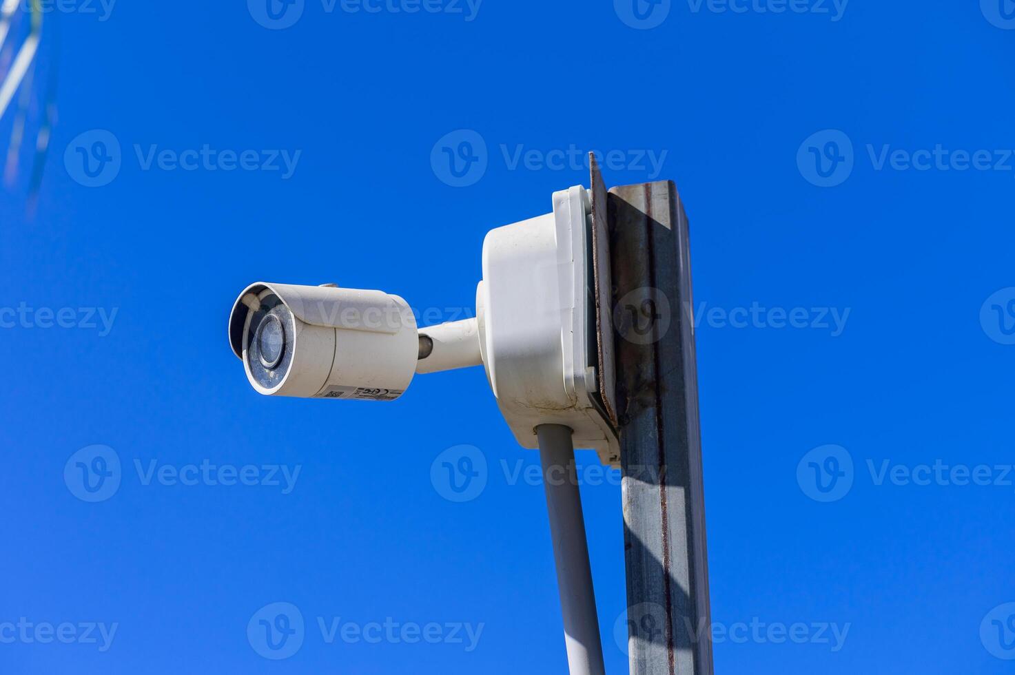 Surveillance camera mounted against clear blue sky in a modern urban setting photo