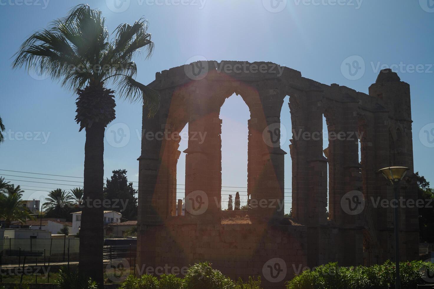 Exploring the sunlit ruins of a historic structure surrounded by palm trees at midday photo