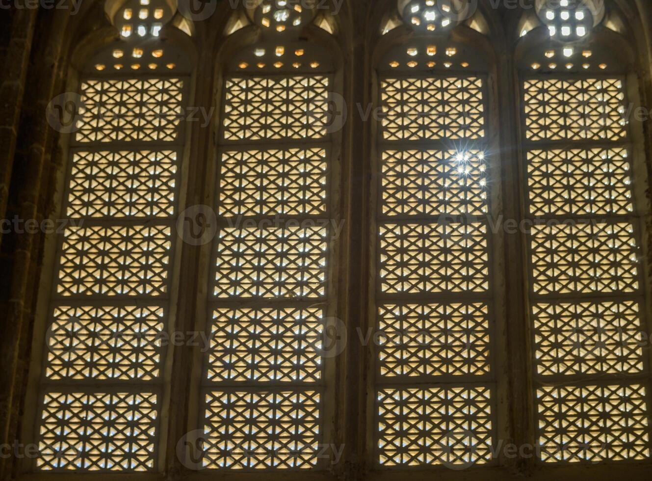 Intricate geometric patterns of stained glass windows illuminating an ancient cathedral during golden hour photo