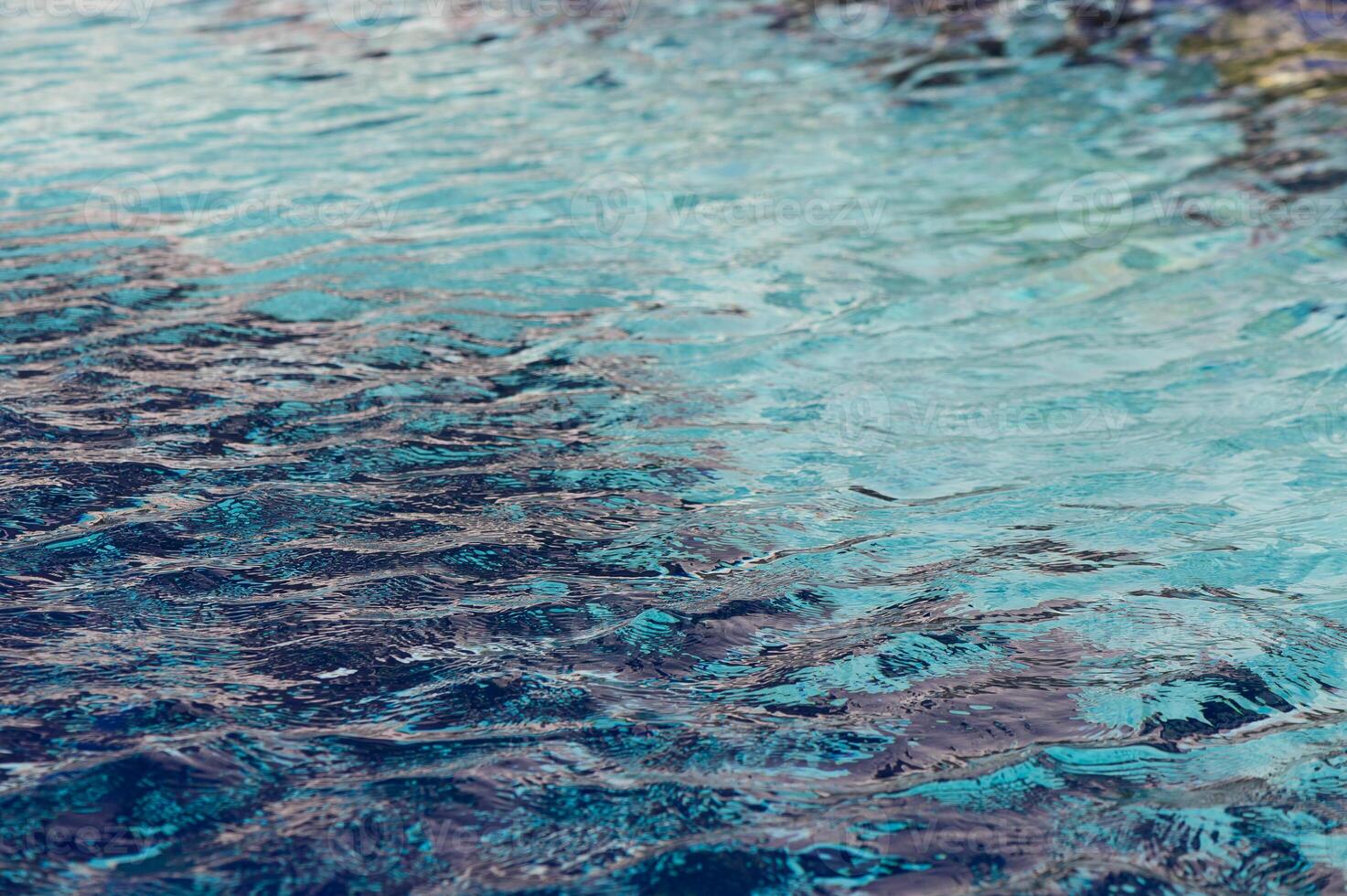 Gentle ripples dance on a tranquil blue water surface under the warm glow of sunlight at a serene coastal setting photo