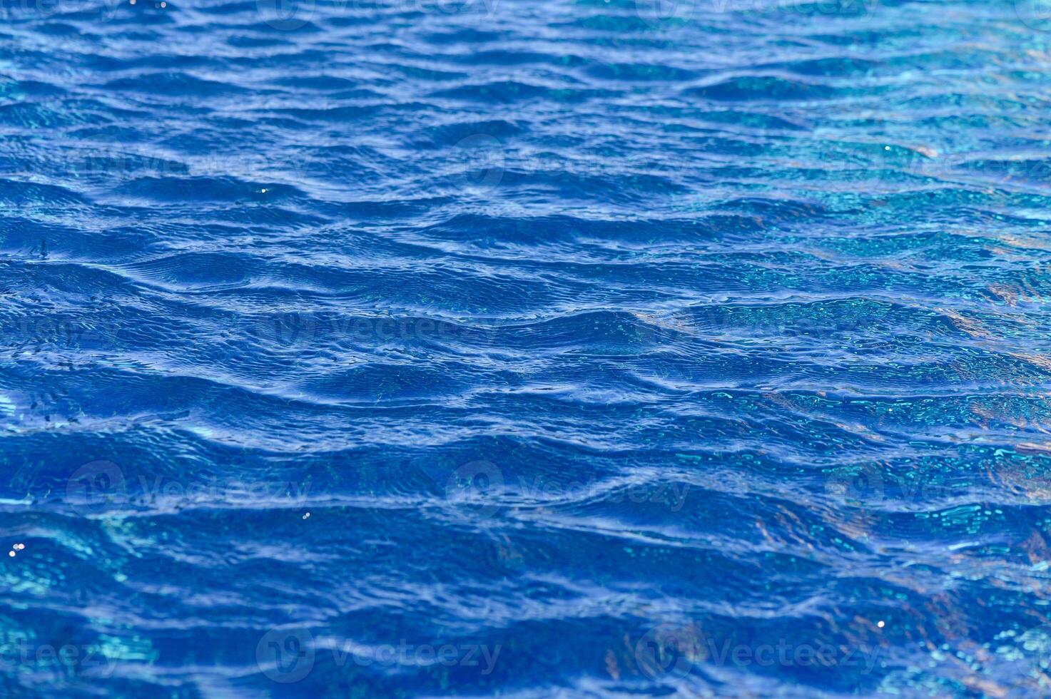 Gentle ripples dance across the vibrant blue water under a bright sun on a serene summer afternoon photo