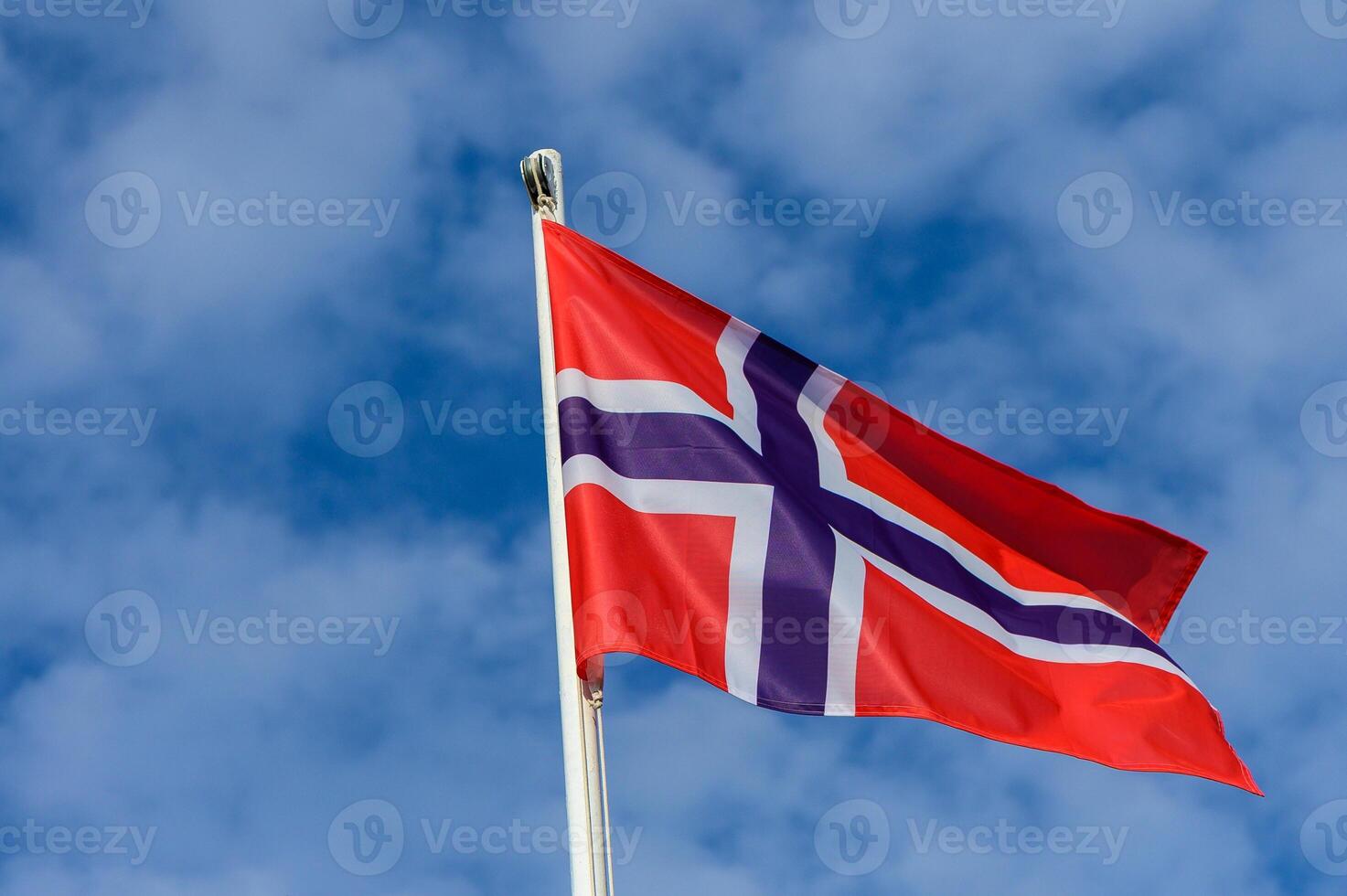 Norwegian flag waving proudly against a backdrop of clear blue skies on a bright sunny day in Norway photo